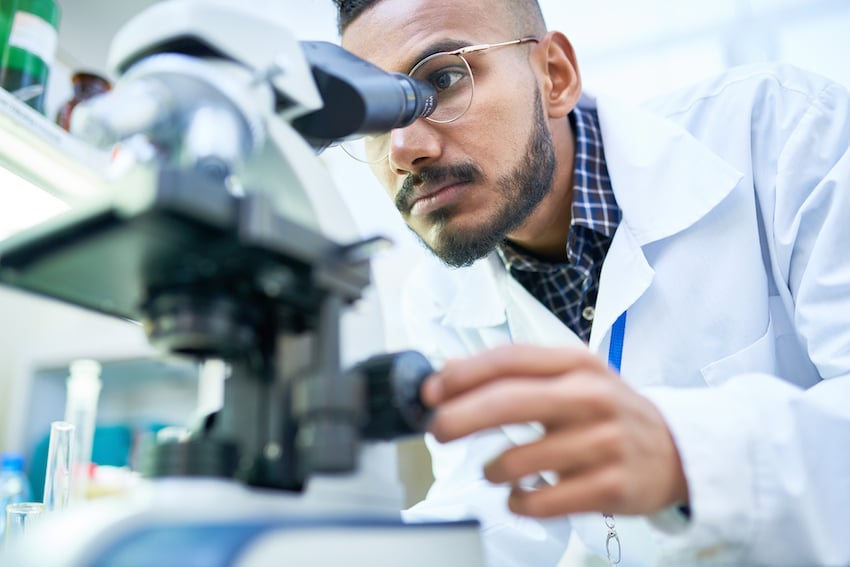 man looking through a microscope to illustrate biotechnology trends